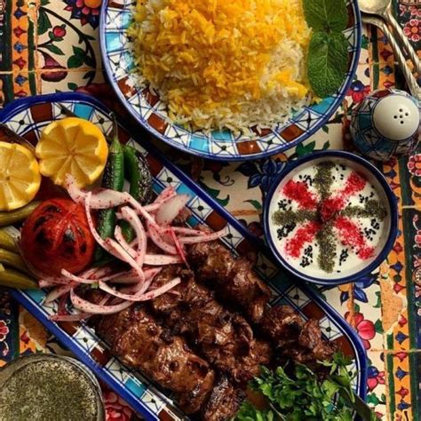 two plates filled with meat, rice and vegetables on top of a colorful table cloth