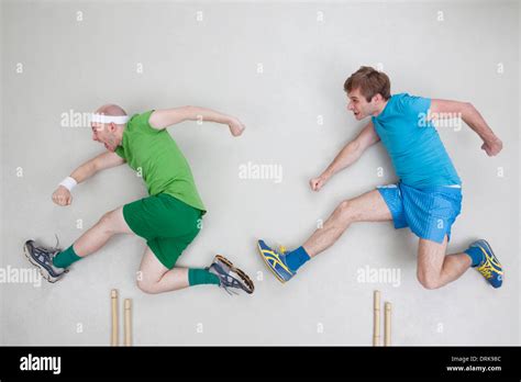 Two men jumping over hurdles Stock Photo - Alamy