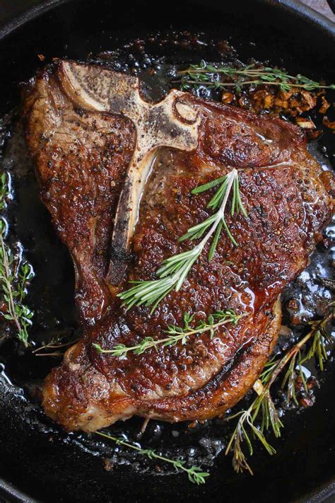 Pan seared T-bone Steak in a cast-iron pan showing a beautiful golden ...