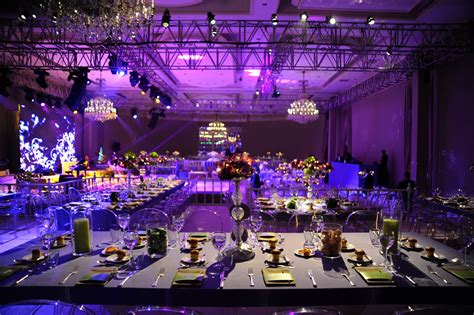 a banquet hall set up for an event with purple lighting and chandeliers on the ceiling