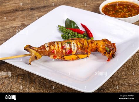 Grilled squid skewer with sauce and hebs Stock Photo - Alamy