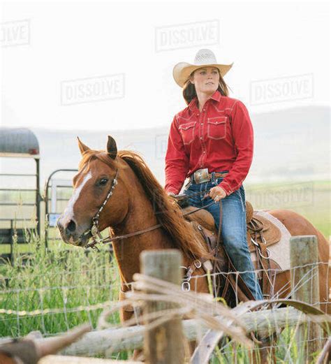 Caucasian cowgirl riding horse on ranch - Stock Photo - Dissolve