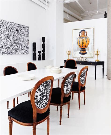 a white table with black chairs and a painting on the wall
