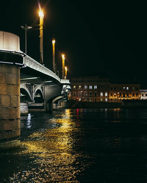 Arched bridge over river in illuminated city at night · Free Stock Photo