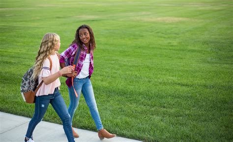 Two diverse school kids walking and talking together on the way ...