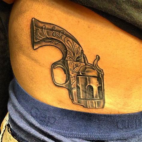 Revolver tattoo located on the waist, illustrative