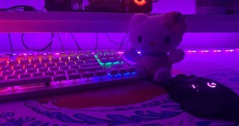 a hello kitty stuffed animal sitting next to a computer keyboard with purple lights on it