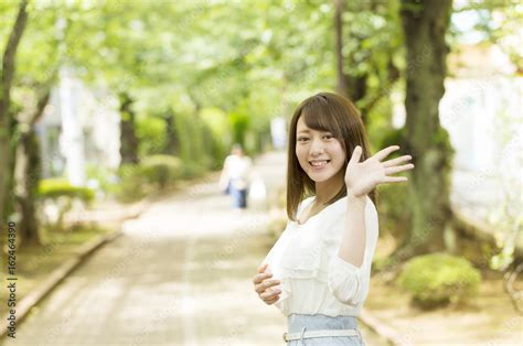 振り返り手を振る笑顔の女性 屋外 緑 Stock 写真 | Adobe Stock