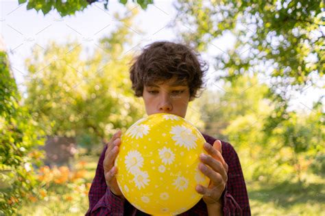 young boy blowing into the balloon o | Stock Photos ~ Creative Market