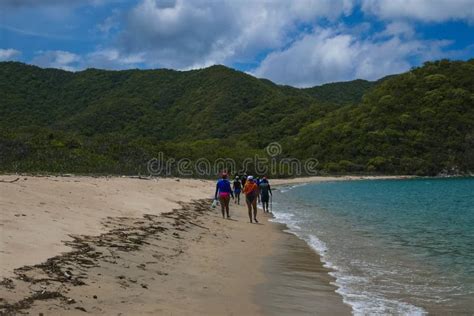 A Group of People Walking Along the Shore of the Beach Stock Photo ...