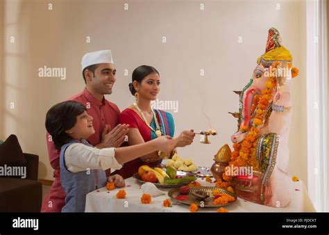 Family performing aarti on Ganesh chaturthi where the child holds the ...