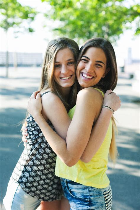 "Young Female Friends Embracing Together Standing In A Park." by ...