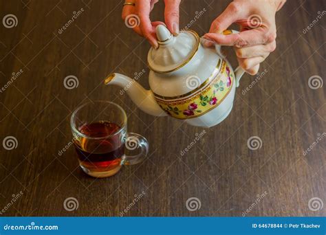 Old-style Porcelain Kettle Pouring Tea From Jug To Cup Of Tea Stock ...