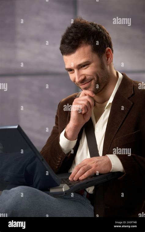 Happy guy smiling with laptop Stock Photo - Alamy