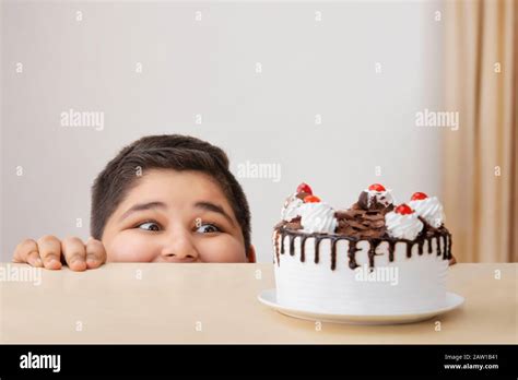 Young boy looking hungrily at a cake kept on the table. (Obesity Stock Photo - Alamy