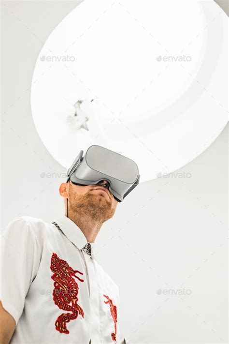 A low angle vertical photo of a futuristic cool male doctor wearing VR goggles in a hospital ...