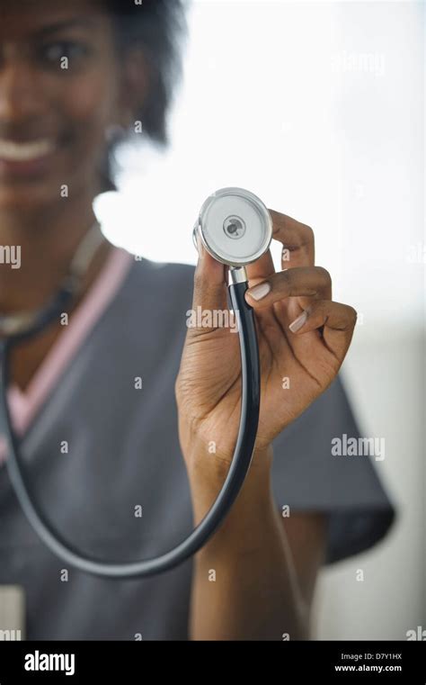 Black nurse holding up stethoscope Stock Photo - Alamy