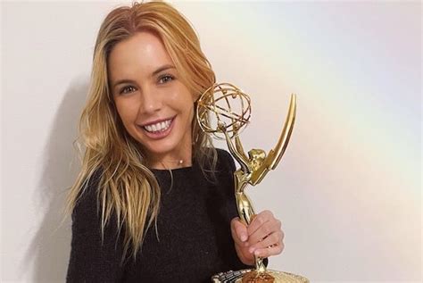 a woman holding an award in her right hand and smiling at the camera ...