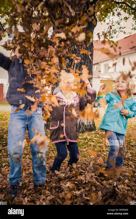 Three children throwing autumn leaves Stock Photo - Alamy