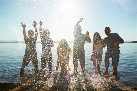 Young people standing in the water and splashing water - Stock Photo ...