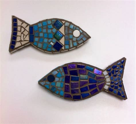 two fish shaped brooches sitting on top of a table