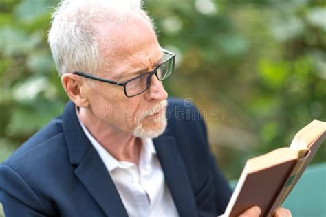 Man Reading a Book Outdoors Stock Image - Image of eyeglasses, senior ...