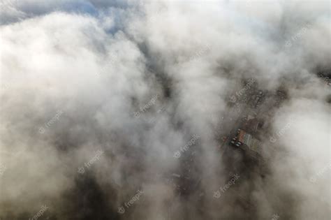 Premium Photo | Top aerial view of fluffy white clouds over modern city with high rise buildings.