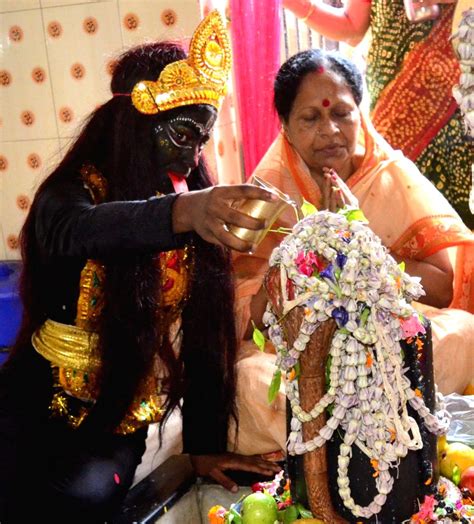 A man dressed up as Goddess Kali, performs rituals while giving water ...