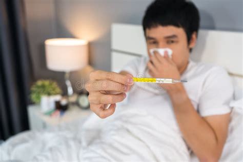 Sick Man Using Thermometer and Showing High Temperature in Bed Stock Photo - Image of ...