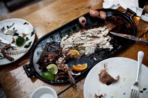 a pan with food on it sitting on top of a table next to plates and utensils