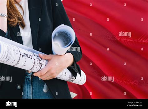 Bahraini Architect woman holding blueprint against Bahrain waving flag background. Construction ...