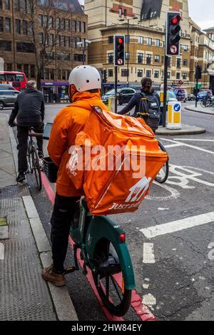 Just Eat courier delivery rider in orange uniform and Just Eat Scooter ...