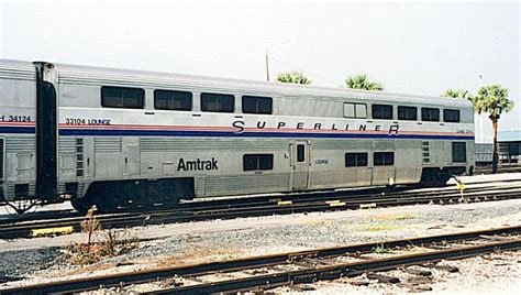 an amtrak train is parked on the tracks near some palm trees and other ...