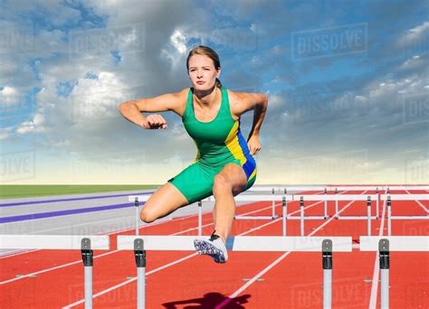 Runner jumping over hurdle on track - Stock Photo - Dissolve