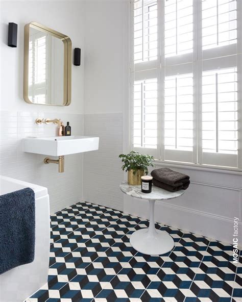 All white bathroom with contrasting patterned floor tiles in blue, white and black. The ...