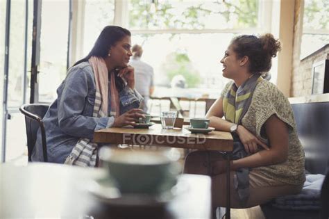 Women friends drinking coffee and talking at cafe table — sitting, side view - Stock Photo ...