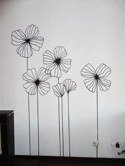 three metal flowers on a white wall next to a black and white dresser ...