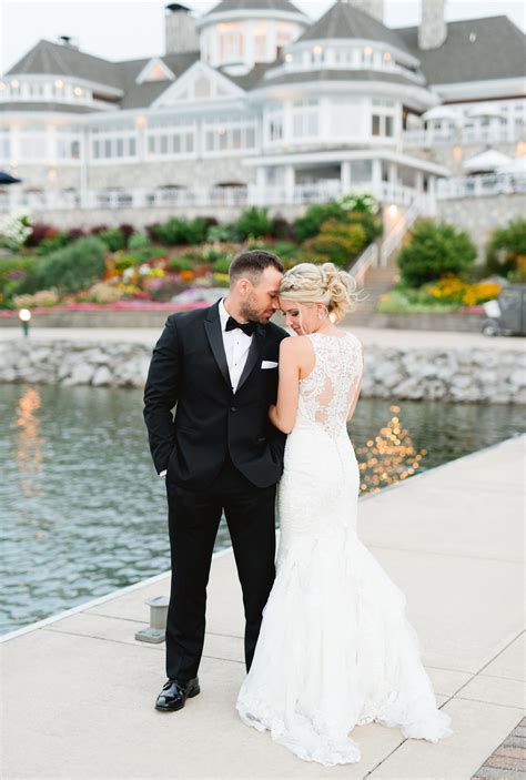 a bride and groom standing next to each other in front of a large house on the water