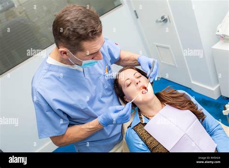 Dentist performing teeth treatment with female patient open mouth with ...