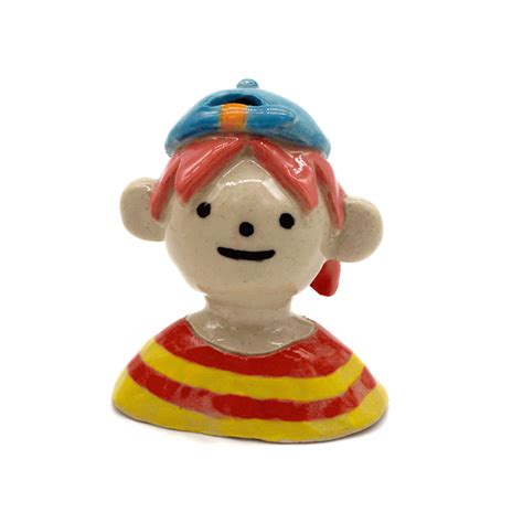 a ceramic figurine with a red and yellow striped shirt on it's head