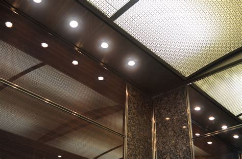 This custom elevator interior has ultra gloss wood panels reflecting the light from a suspended ...