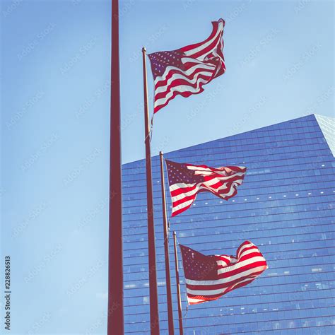 American flag in downtown skyline on background. Stock Photo | Adobe Stock