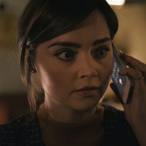 a woman holding a cell phone to her ear and looking at the camera with an intense look on her face