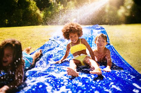 Afro girl and friends playing on a water slide | Our Children