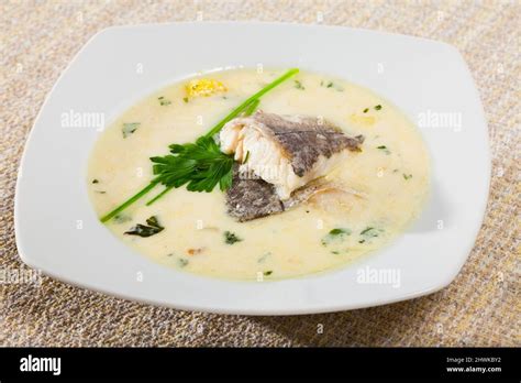 Creamy soup with white fish hake served with greens at plate Stock ...