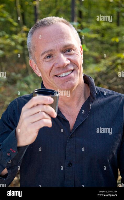 Older Man Walking in Woods Drinking from a Cup Stock Photo - Alamy