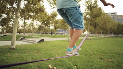 Guy walks on slackline at public park 1305367 Stock Video at Vecteezy