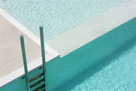 Swimming pool ladder at deep end separated from shallow pool by ledge ...