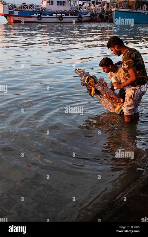 a statue of a goddess is placed in the Ganges River as part of a Hindu ...