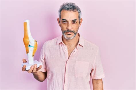 Handsome Middle Age Man with Grey Hair Holding Anatomical Model of Knee Joint Thinking Attitude ...